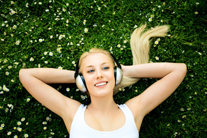 Woman enjoying greenery and listening to music.
