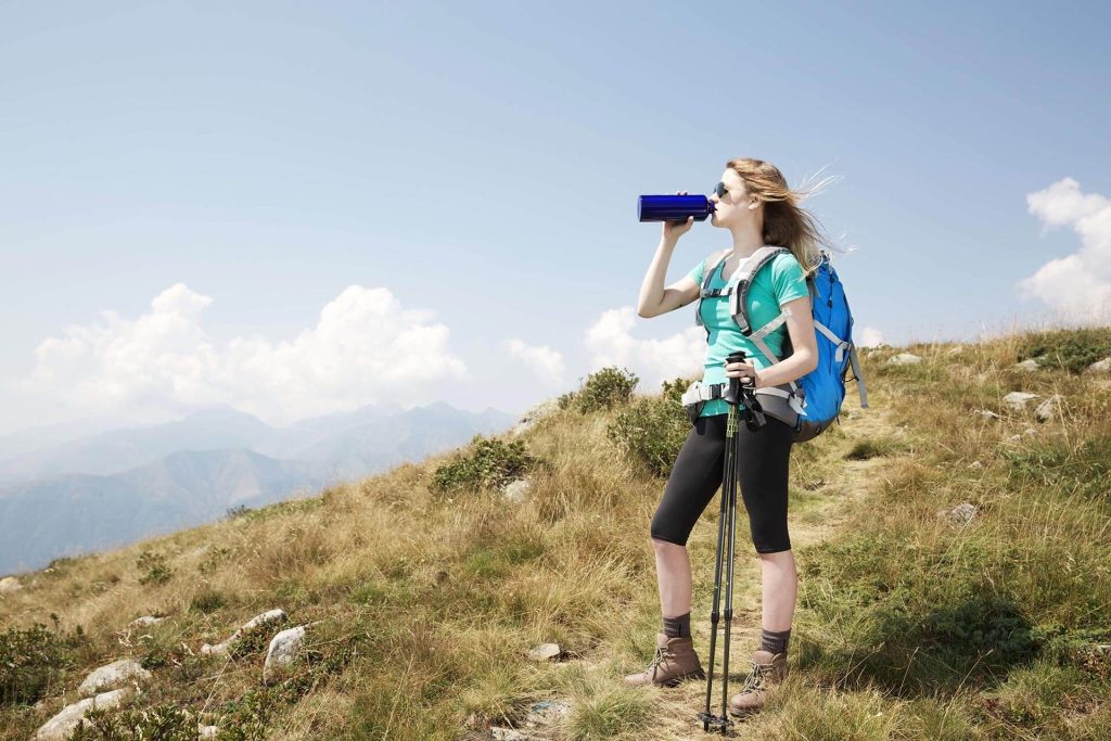 Woman hiker having a cool refreshing drink.