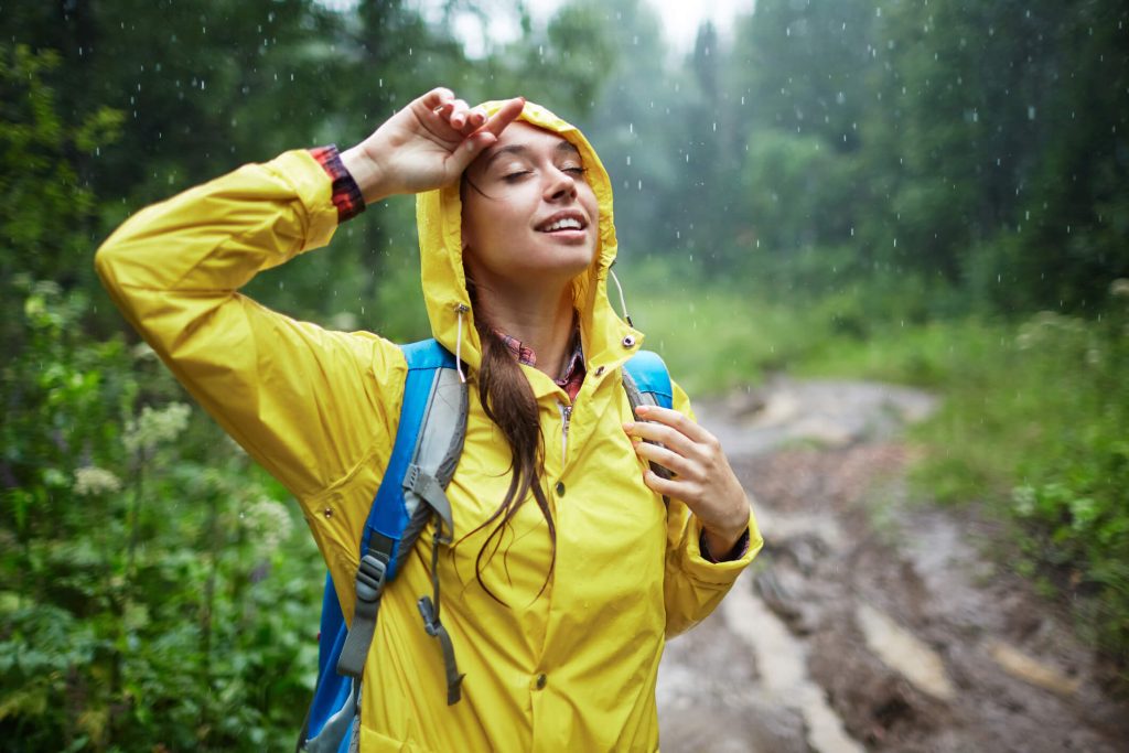Young woman with backpack enjoying rainy weather